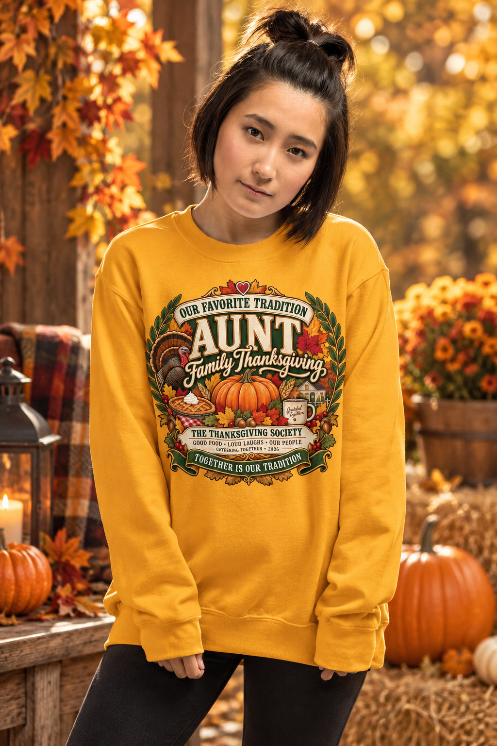 A woman modeling a golden yellow crewneck sweatshirt with a large Thanksgiving graphic on the front, set against a plain white background.