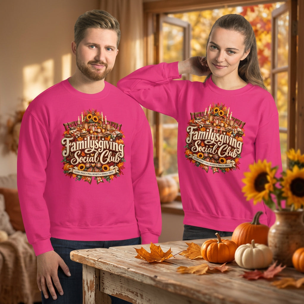 A man and a woman modeling matching bright pink crewneck sweatshirts with a large graphic on the chest that reads 'Familygiving Social Club' in white script over an illustrated multicolor design. The background is solid white.