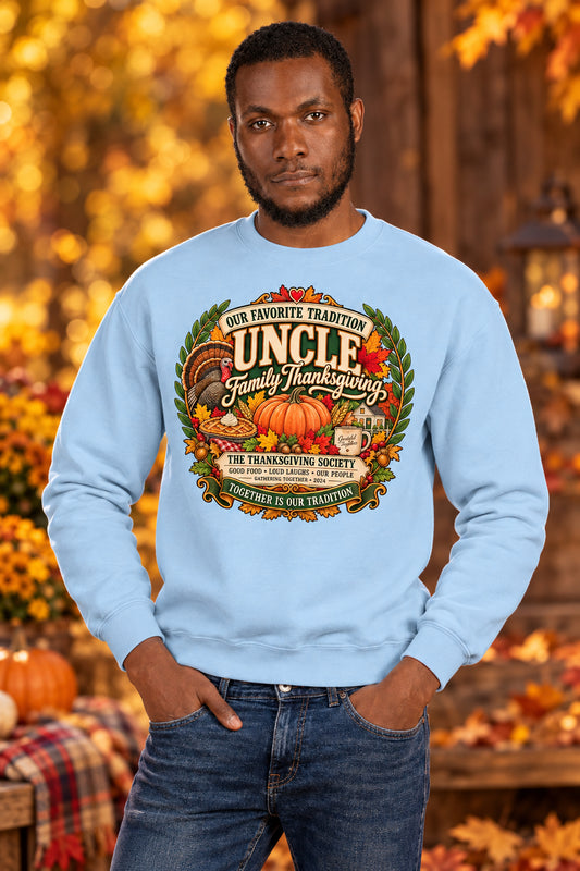 A man wearing a light blue crewneck sweatshirt with a large, colorful graphic on the chest that reads 'Uncle Family Thanksgiving' with pumpkins, autumn leaves, and a turkey, paired with dark blue jeans, against a plain white background.