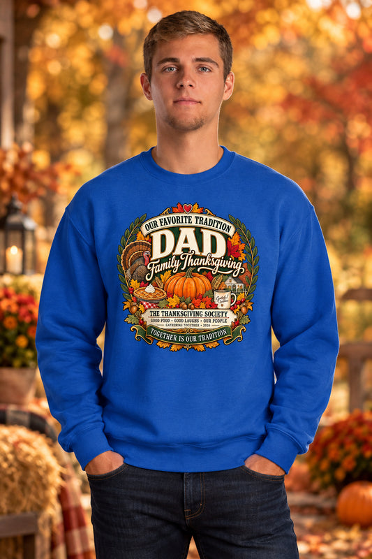 A man wearing a royal blue crewneck sweatshirt with a large, detailed Thanksgiving graphic on the chest. The graphic features pumpkins, turkeys, autumn leaves, and text reading 'Our Favorite Tradition DAD Family Thanksgiving' and 'The Thanksgiving Society'.